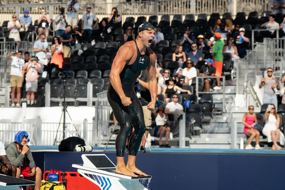 Cody Miller raises his arms in victory on a starting block at a makeshift Olympic pool in Las Vegas.