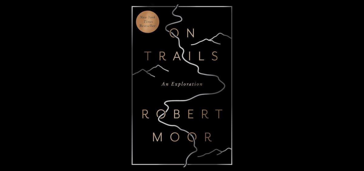 A winding dirt path cuts through a dense forest landscape.