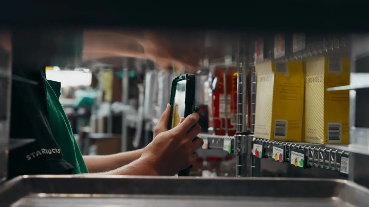 A Starbucks employee conducts manual inventory checks inside a retail store