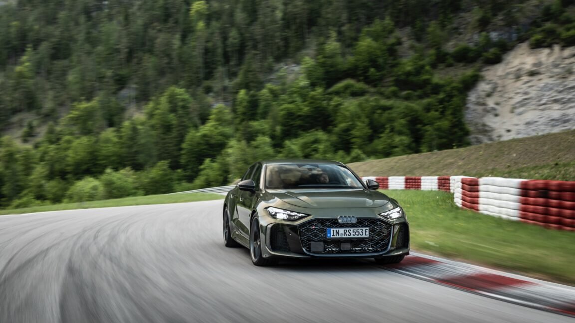 The 2027 Audi RS5 plug-in hybrid is shown from a front three-quarter angle on a paved road.