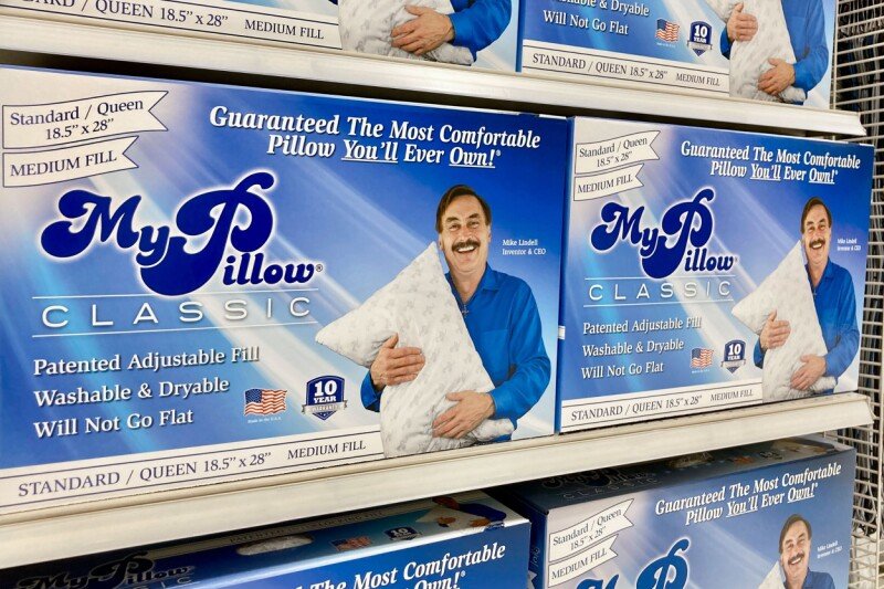 A MyPillow box sits next to a laptop displaying a ransomware demand notice.