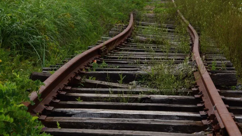 Irish Rail trains travel along suburban tracks near a station.