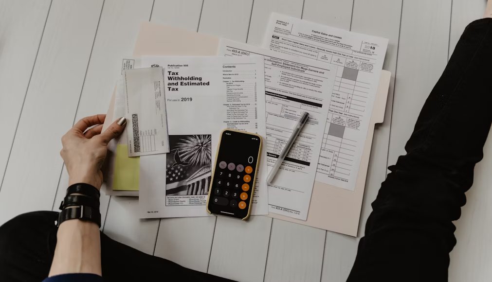 A desk displays organized financial documents and digital folders for tax record management.
