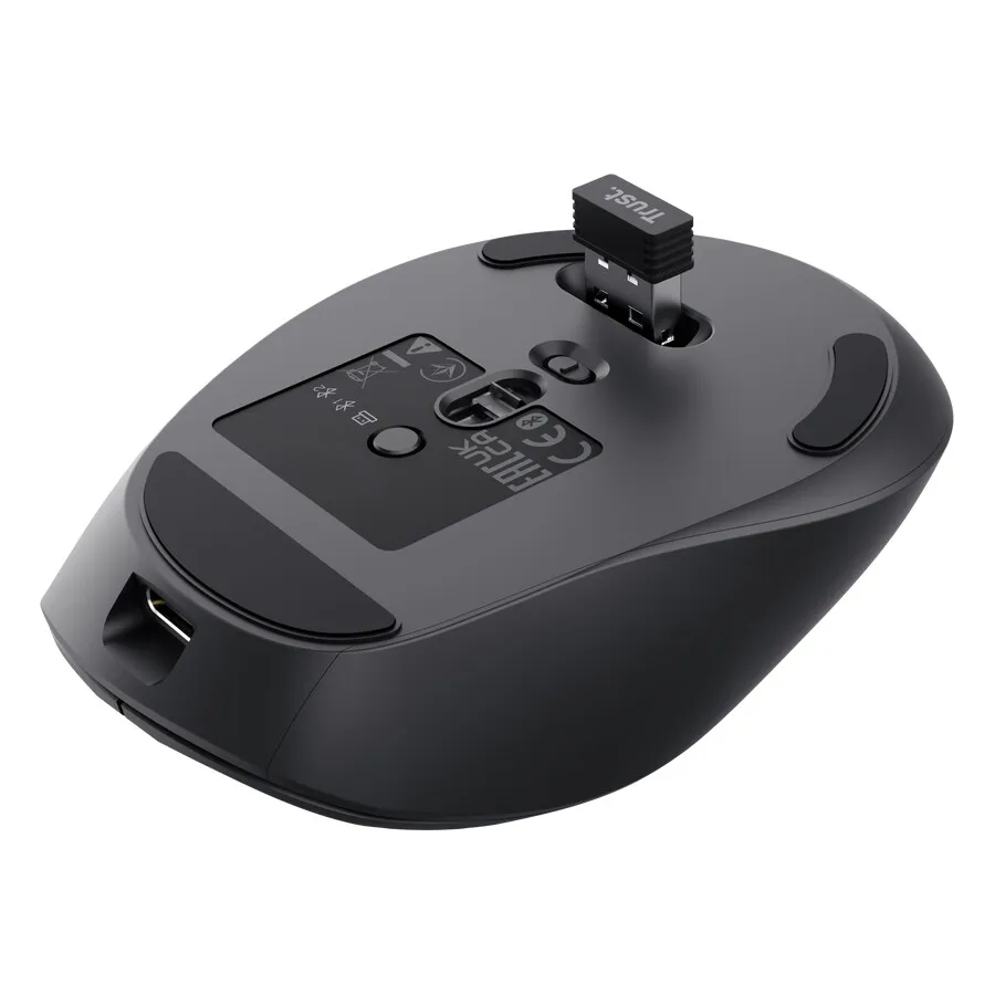 A Trust Zevo rechargeable multi-wireless mouse rests on a desk next to its wireless receiver and charging cable.