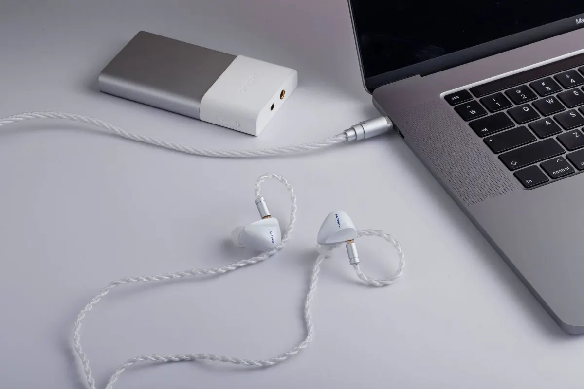 Activo Scoop wired earbuds and their included carrying case rest on a flat surface alongside the audio cable.