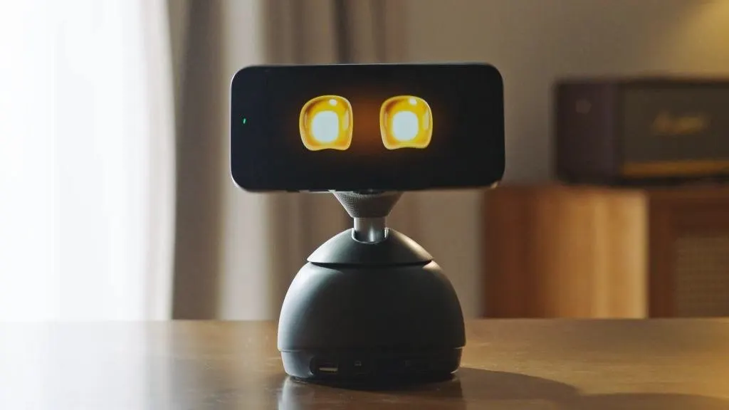 Smartphone mounted on a motorized base that physically tracks user movement across a workspace while charging.