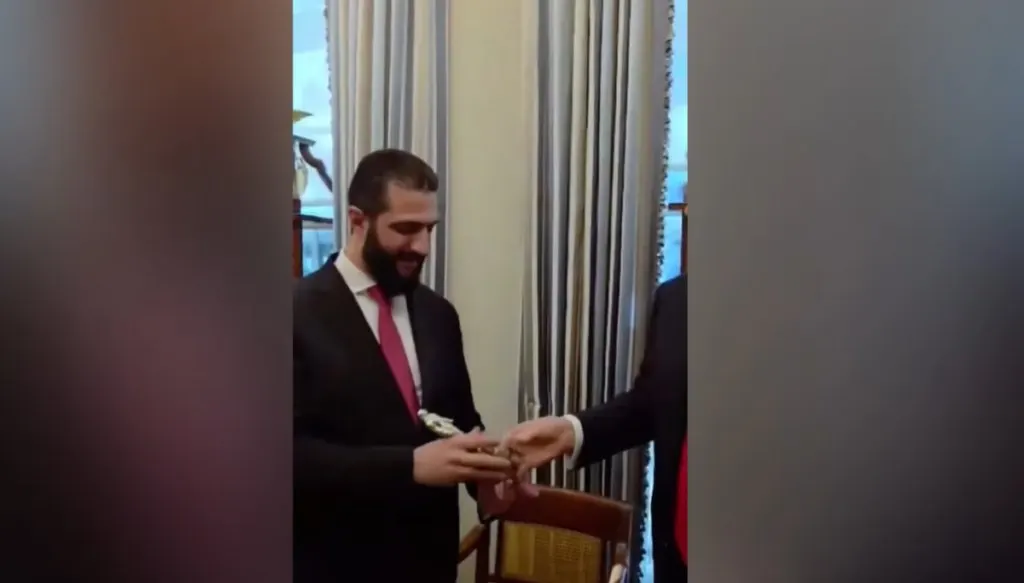 Ahmed al-Sharaa receiving a branded fragrance gift from Donald Trump during a diplomatic meeting.