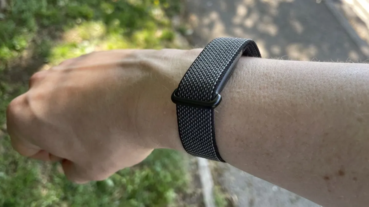 The Google Fitbit Air smartwatch displays fitness metrics and weather data on its screen.