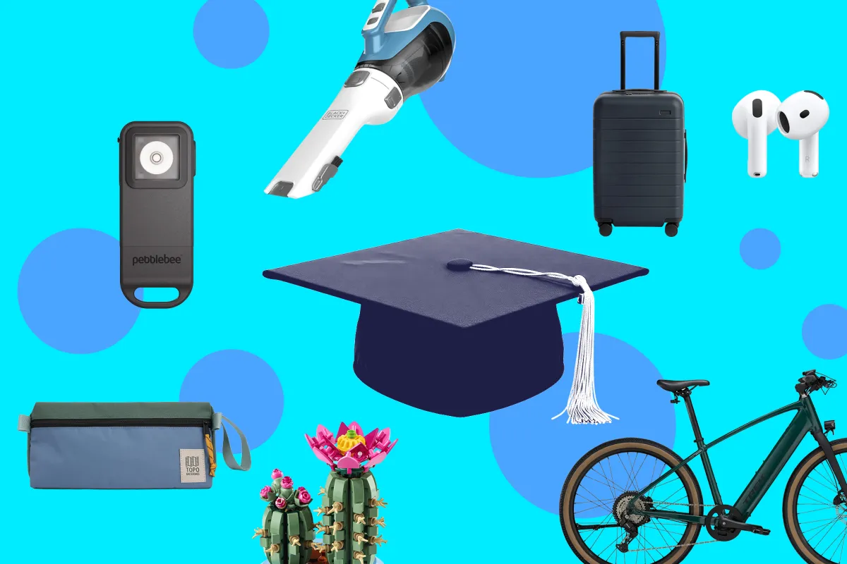 A selection of graduation gifts including a watch, diploma cover, and cap and gown laid out on a surface.