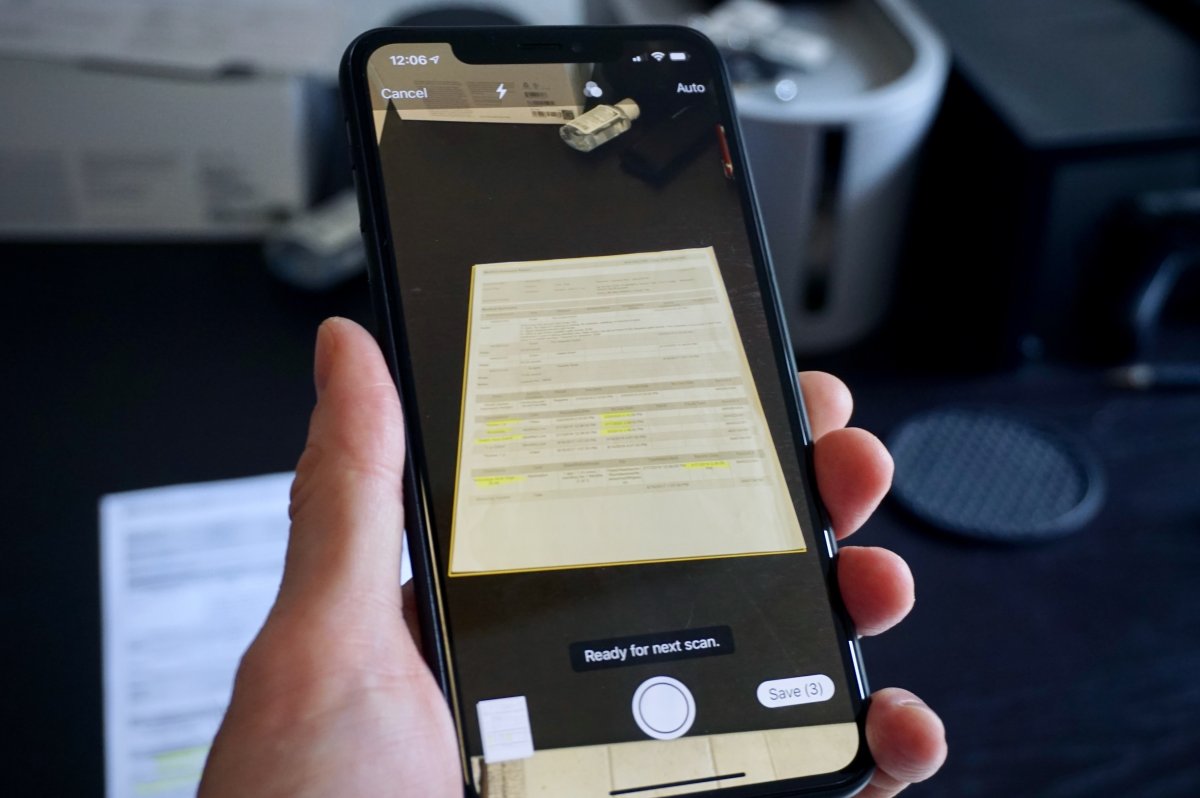 iPhone screen showing the native document scanner capturing a physical paper to create a PDF file.