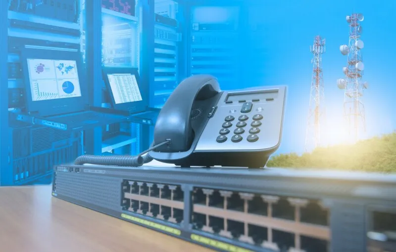 A junior technician configures network switches in a medical clinic server room.