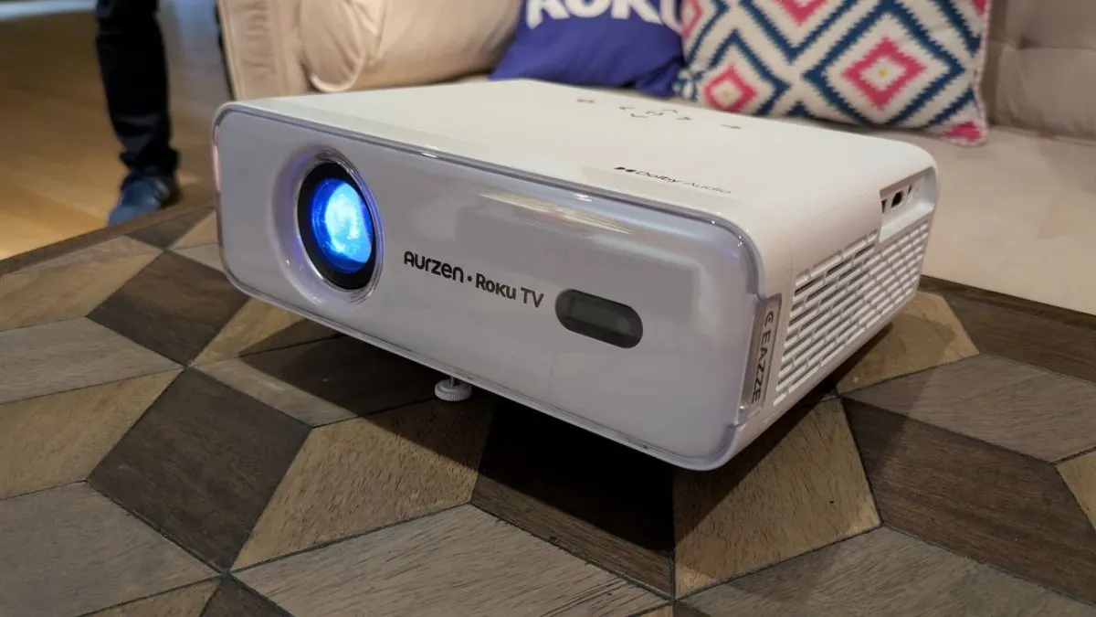 Two compact Roku projectors and a streaming remote control displayed on a table.