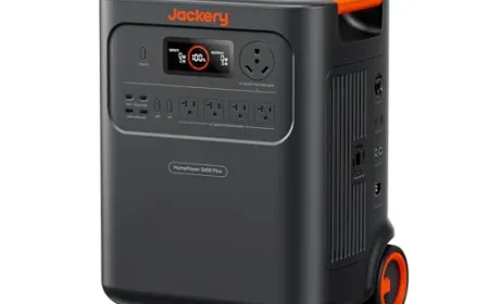 A whole home backup power station unit mounted on a garage wall with connected battery modules and wiring.