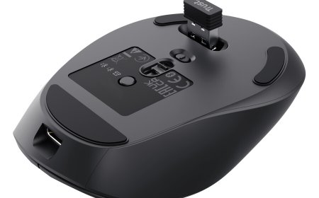 A Trust Zevo rechargeable multi-wireless mouse rests on a desk next to its wireless receiver and charging cable.