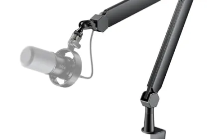 A desktop microphone arm kit is mounted on a desk, displaying adjustable joints and a professional studio microphone.