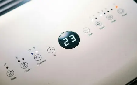 A portable air conditioner sits near a window with its exhaust hose connected for summer cooling.