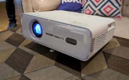 Two compact Roku projectors and a streaming remote control displayed on a table.