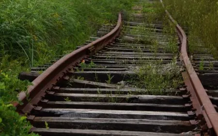 Irish Rail trains travel along suburban tracks near a station.