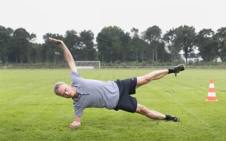 Older adults perform gentle bodyweight exercises while reviewing a digital training plan on a tablet.