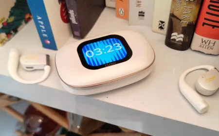 Wireless earbuds inside a charging case with a touchscreen display.