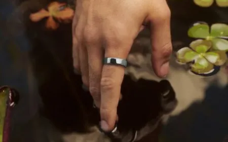 The titanium Oura Ring 5 smart ring sits beside its aluminum charging case.