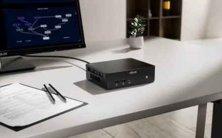 A compact mini desktop computer rests on a workspace next to a keyboard and monitor.