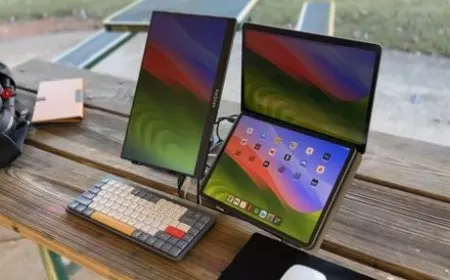 A portable monitor connected to a laptop on a temporary desk with multiple cables and power adapters.