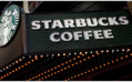 A Starbucks employee scans inventory using a handheld device at a retail location.