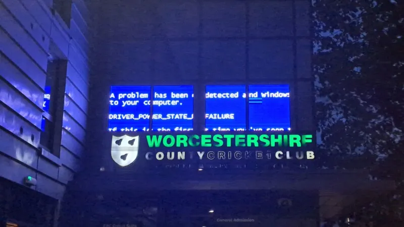 A Windows halt screen displays on a public digital sign at a historic cricket club during a driver power failure.