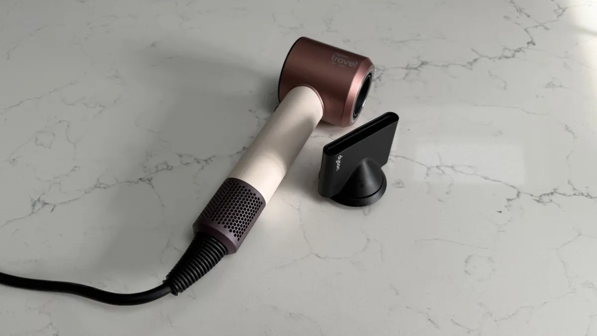 Dyson Supersonic Travel hair dryer in a compact silver design with an attached concentrator nozzle.