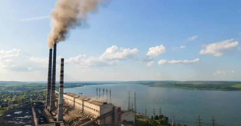 Smokestacks at a coal power plant release steam during daytime operations.