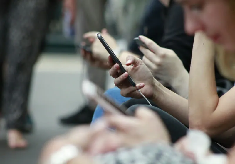 A smartphone displays a social media prohibition symbol next to official UK youth safety guidelines.