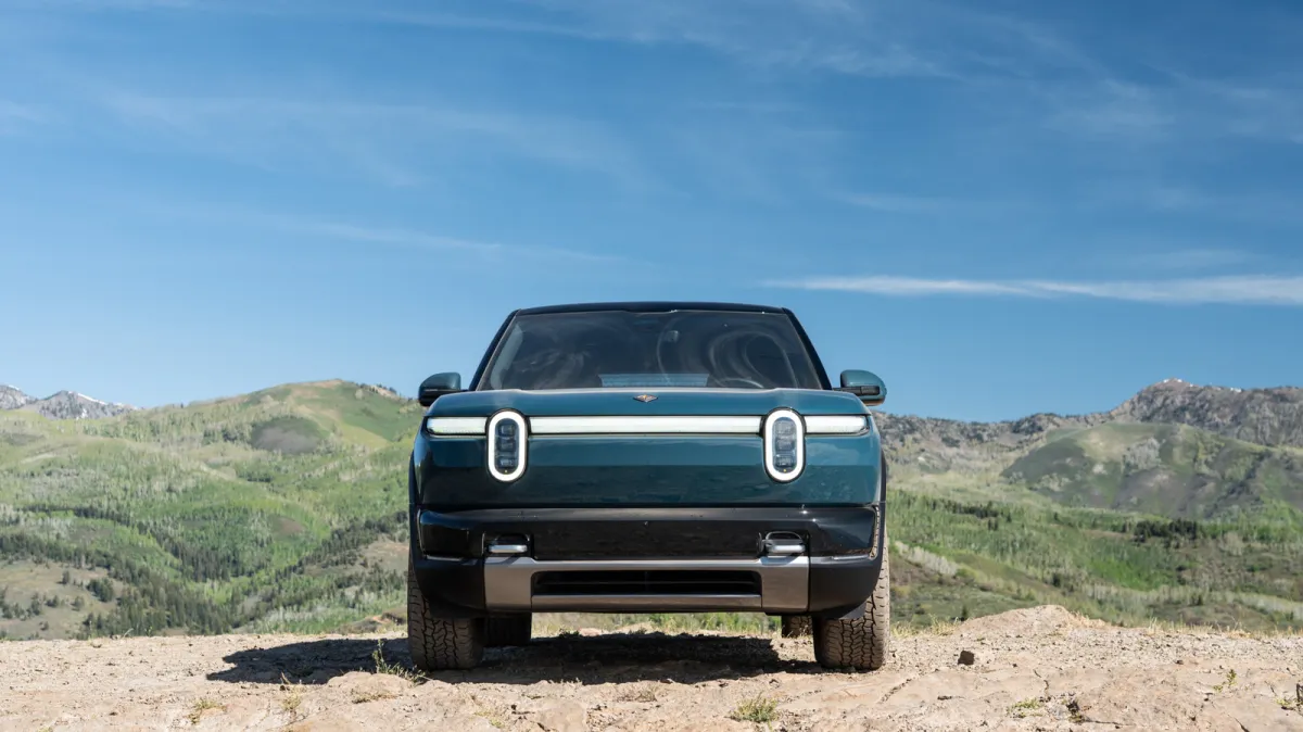 The 2027 Rivian R2 electric SUV is parked on a paved road during a first drive review.