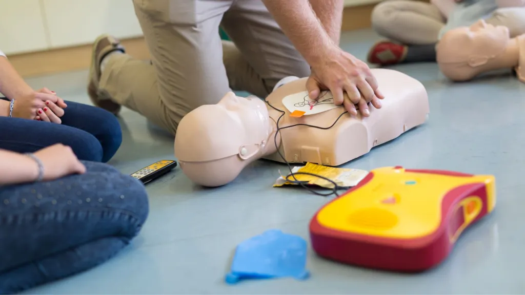 Emergency responders perform CPR while a bystander activates the medical response system.