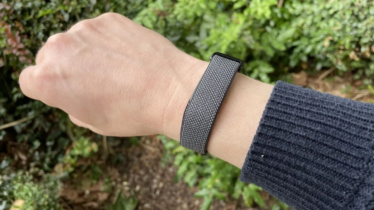 The Google Fitbit Air screenless fitness band rests on a display stand. Its minimalist design emphasizes comfort.