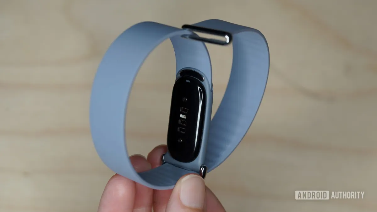 A Fitbit Air band is attached to an analog watch by slipping through the spring bars after removing the original strap.