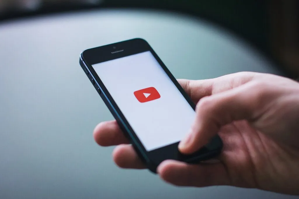 A teenager uses a smartphone displaying social media applications next to age restriction warnings.