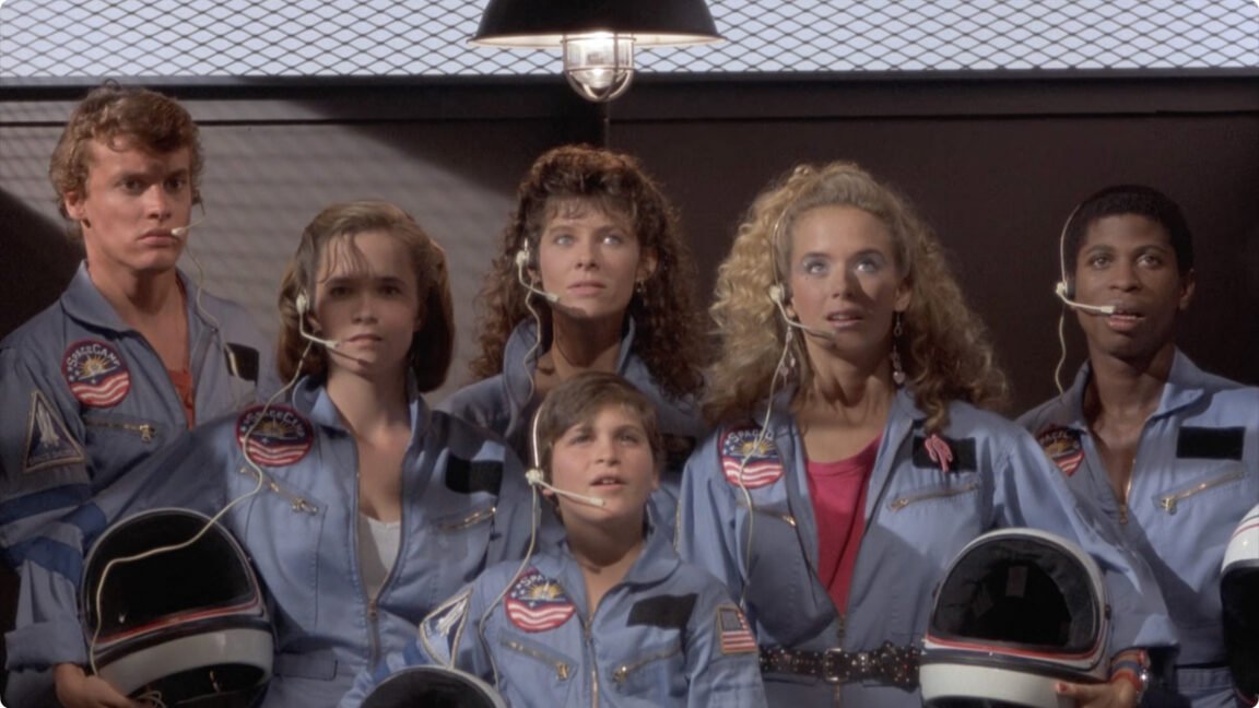This promotional poster for the 1986 film SpaceCamp depicts young astronauts in a training facility.