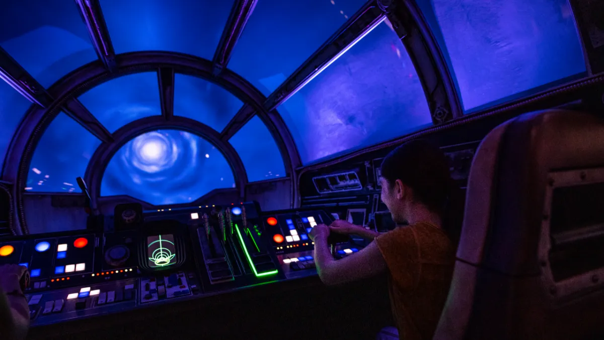 This screenshot shows the updated Millennium Falcon Smugglers Run attraction featuring The Mandalorian and Grogu.