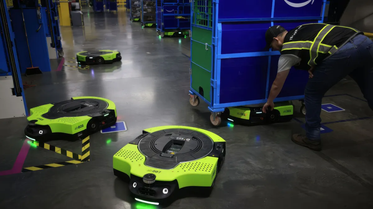 An autonomous Proteus warehouse robot navigates a facility while transporting a heavy inventory cart.