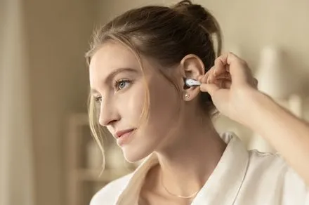 Shokz OpenDots 2 open-ear earbuds are shown with a flexible clip design and charging case.
