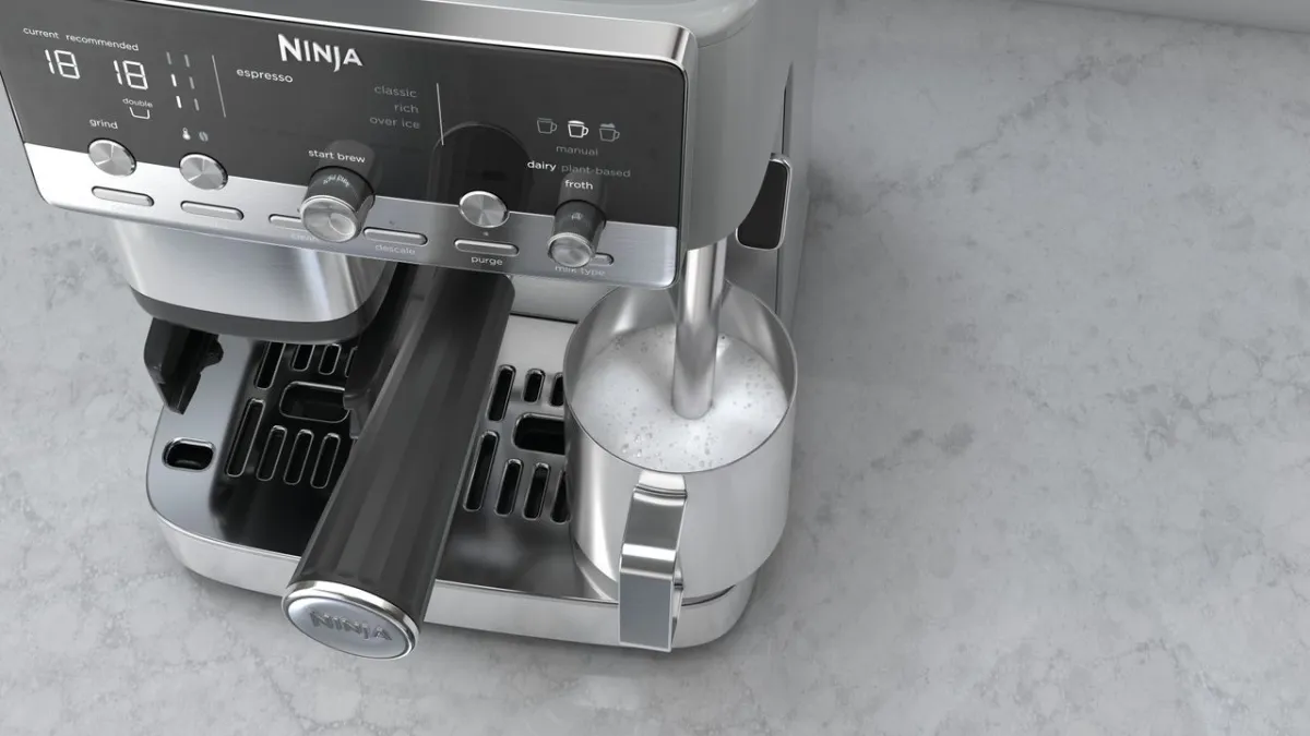 The compact Ninja Luxe Cafe Mini Plus espresso machine displays its control panel and integrated milk frothing spout.