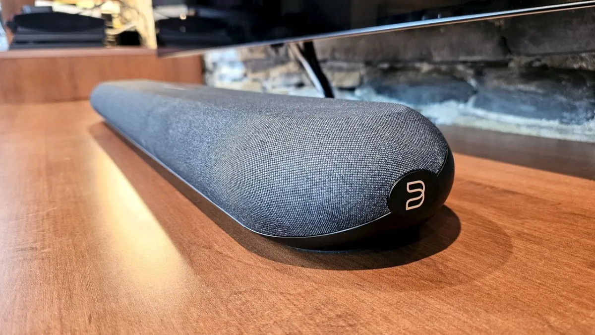 The compact Bluesound Pulse Cinema Mini soundbar is displayed from the front, showing its fabric grille and control panel.