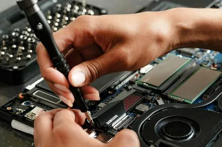 A person uses standard tools to repair a smartphone on a workbench.