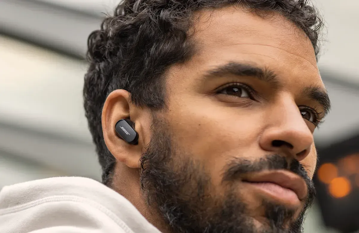 The Bose QuietComfort Earbuds II sit next to their charging case.