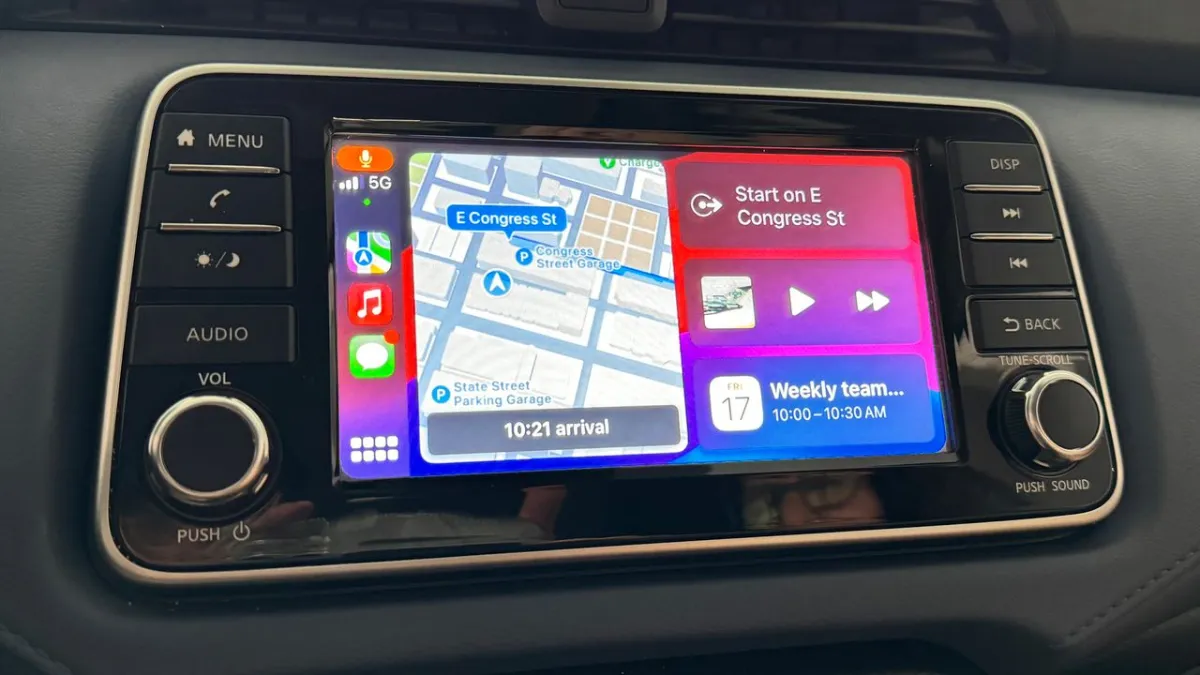A vehicle dashboard screen displays the Apple CarPlay interface while a video streaming application runs.