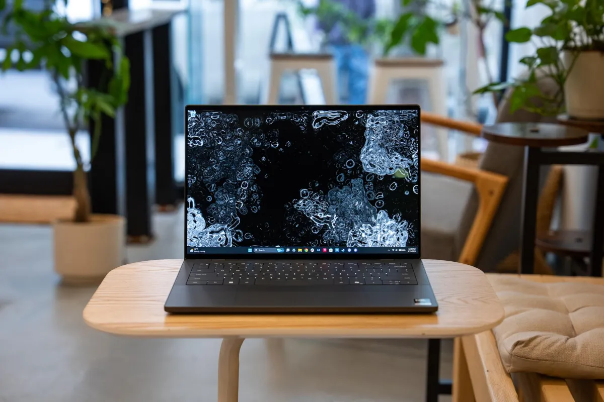 A silver Dell XPS 14 laptop rests open on a desk with its screen illuminated.