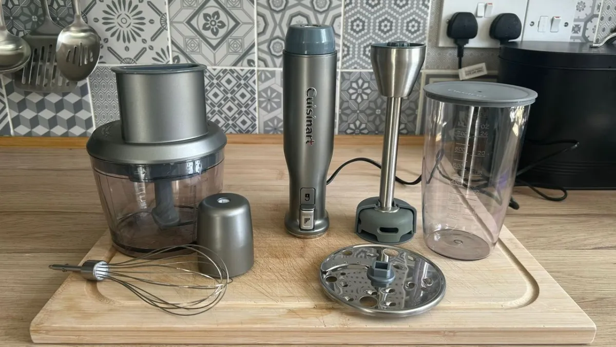 A silver Cuisinart immersion blender with blending and whisk attachments rests on a kitchen counter.