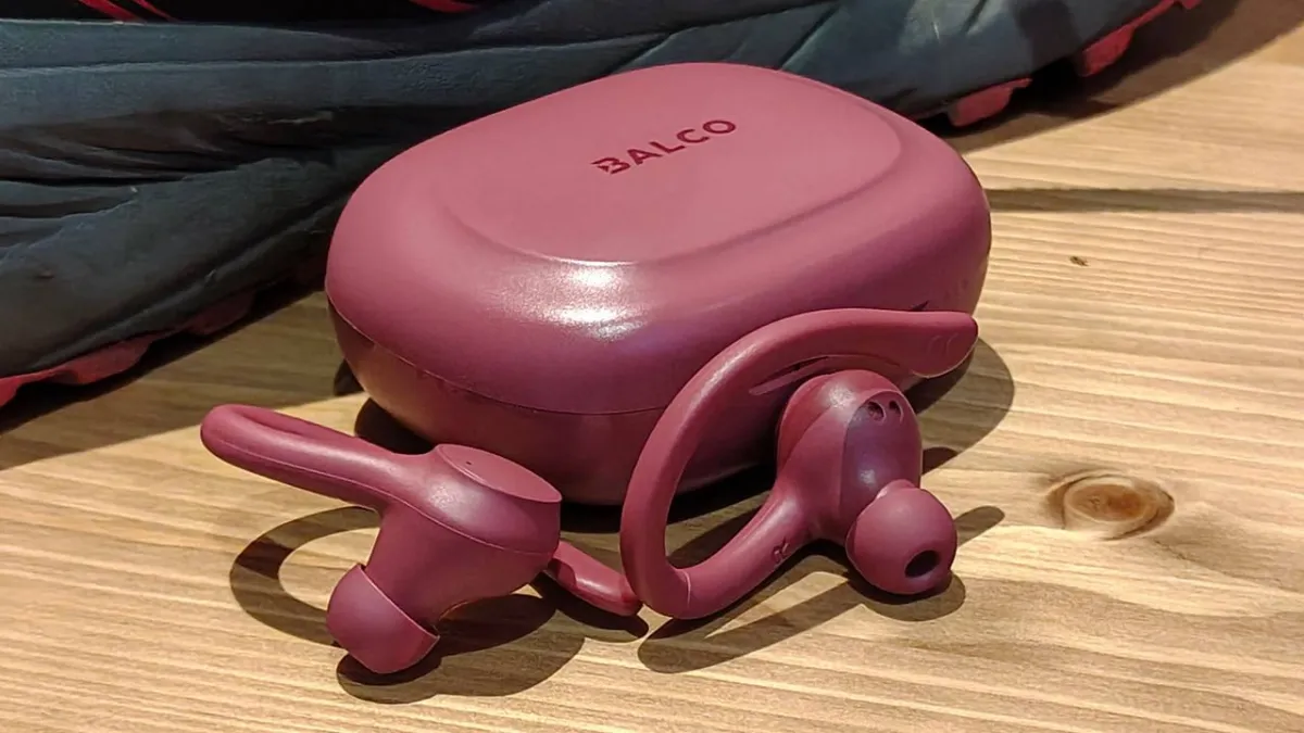 A pair of budget sports earbuds rests on a testing surface during acoustic performance evaluation.