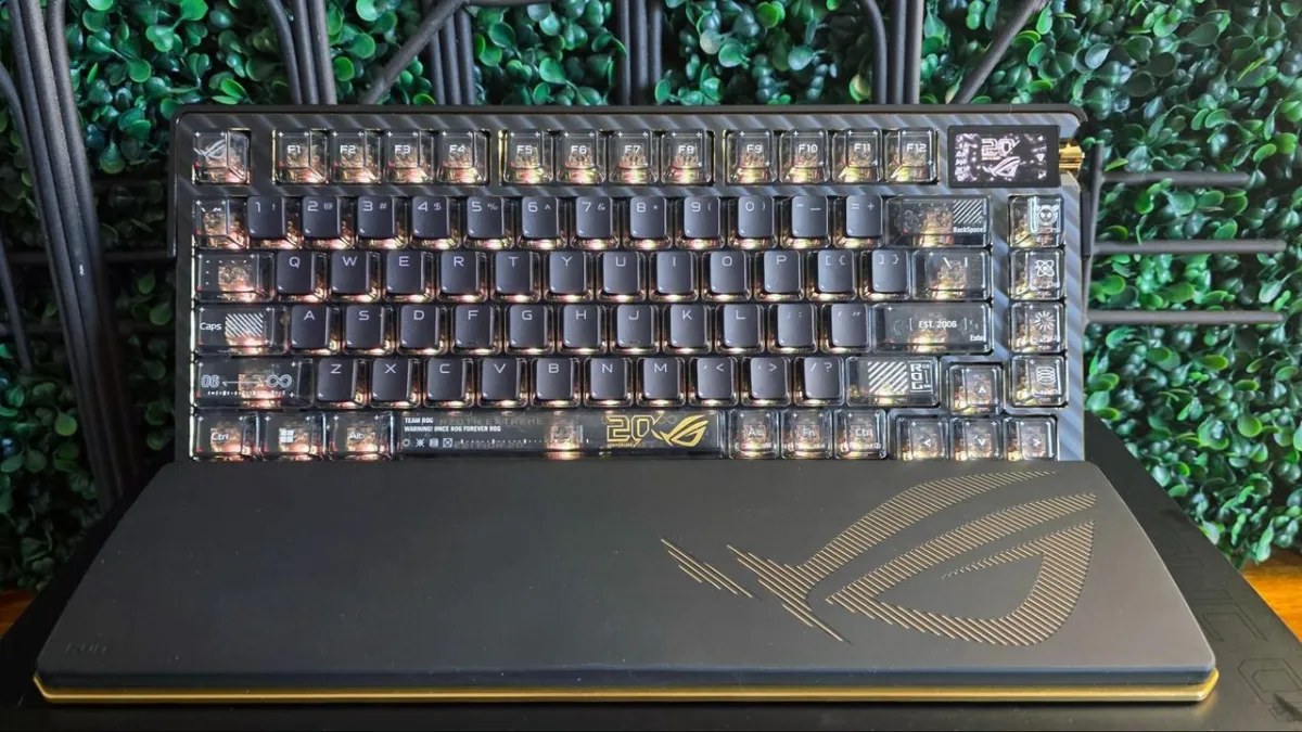 Asus ROG Azoth Extreme Edition 20 keyboard featuring gold accents, transparent keycaps, an OLED screen, and a wrist rest.